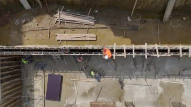 İnşaat alanındaki bir binanın temellerine beton döken işçilere dikkat edin..