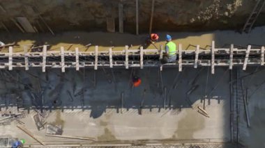 Temel yük duvarlarını ve zemin sistemlerini inşa eden inşaat işçilerine bakın.