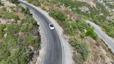 Dağlarla çevrili virajlı yollar boyunca üstü açık bir arabada nefes kesici bir sürüşün tadını çıkar..