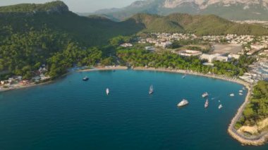 Antalya Kemer 'in sahil şeridi boyunca uzanan altın plajlar ve yatlar üzerindeki huzurlu gündoğumunu görün..