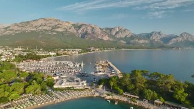Gün doğumunda Antalya Kemer 'in gezinti alanı boyunca uzanan huzurlu altın plajlara ve yatlara bakın..