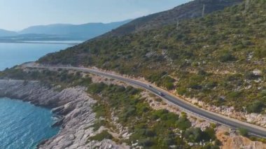 Üstü açık bir arabada nefes kesen masmavi deniz manzaralı bir çift görüyorum..