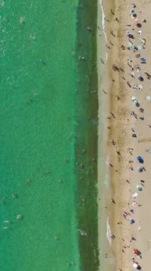 Saf mutluluğa tanık olun. İnsanlar kumsalın tadını çıkarırken, masmavi sularla nefes kesici 4K ile..