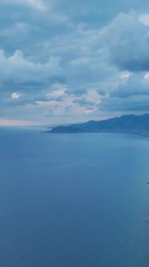 Gökyüzünde bir renk senfonisi deneyimleyin. Bulutlu bir akşam günbatımının hızlandırılmış haliyle dikey biçimde..