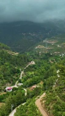 Dağ yağışı sırasında büyüleyici bir köyün büyüsüne tanık olun. Dikey bir hava manzarası olsun..