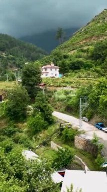 Dağlara kurulmuş yağmura bulanmış bir köyün güzelliğine dalın. Dikey videoda büyüleyici hava manzarası..