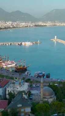 Yukarıdan Alanya 'nın güzelliğini keşfedin. Bu dikey videoda deniz kenarını yatlarla ve tarihi kaleyle gösterin..