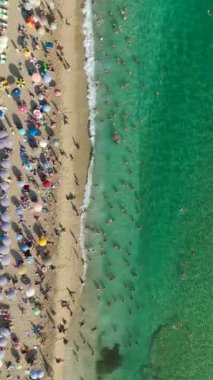 Bu dikey videoda Akdeniz 'in masmavi sularında yüzen insanların 4K' daki deniz kıyısında keyifli anlarında.