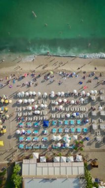 4K plajındaki mutluluğa tanık olun. İnsanlar bu dikey videoda gök mavisi Akdeniz 'in tadını çıkarıyorlar..