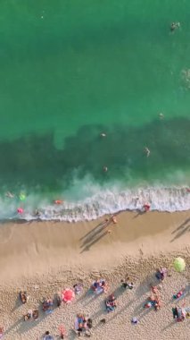 4K 'deki kumsal anlarında keyifli anlar. Gök mavisi sularda yüzen insanların havadan görüntüsü. Yaz tatillerinin tadını çıkarıyorlar..