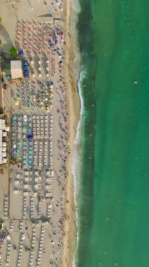 4K 'deki yaz atmosferine kaçın ve bu dikey videoda insanların yüzdüğü ve eğlendiği bir plaj manzarasına bakın..