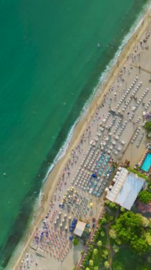 4K 'deki kumsal anlarında keyifli anlar. Gök mavisi sularda yüzen insanların havadan görüntüsü. Yaz tatillerinin tadını çıkarıyorlar..