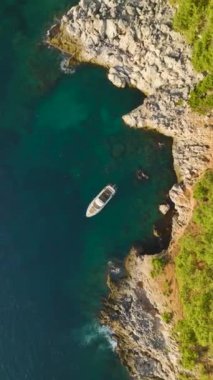 Akdeniz kayalıklarında 4K 'da yatçılık deneyimi. Deniz ve taşın güzelliğini gösteren dikey bir video..