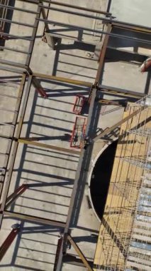 Büyük bir alışveriş merkezi inşa edilirken 4K 'da bir vaha yolculuğuna çıkın. Metal yapı kurulumunun dikey videosu.