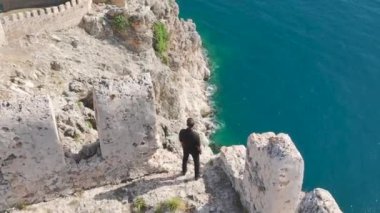 Akdeniz nöbetçisi Alanyas taş muhafızının yanında dur. Huzurlu sulara bakıyor, 4K 'da ele geçirildi..