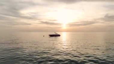 Altın sularda süzülen bir spor teknesine hayret, parlak formu 4K 'da güzel bir turuncu alacakaranlık altında dalgaları kesiyor..