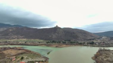 Mtskheta 'nın kucaklamasına girin, sakin nehrin kıyısındaki antik bir katedral zamanın bir göstergesi olarak duruyor, 4K' da çekiliyor..