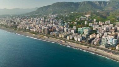 Gün batımını bir kıyı şehrinin üzerinde seyredin, denizi altın rengine çevirin ve binalar parlıyor, hepsi 4K 'da yukarıdan görünüyor..