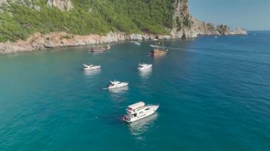 Güneşle sırılsıklam olmuş bir denizde dans eden yatları ve dalgaları görün, arka planda parlayan plajları, hepsi göz kamaştırıcı 4K.