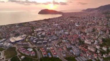 Gün batımında pembe bulutların büyüleyici parıltısı altında, yukarıdan yakalanmış bir Türk şehri..