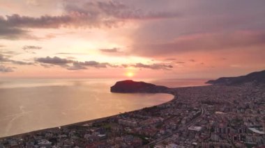 Gün batımında Türk kentinin silueti boyunca sürüklenen pembe bulutların hava görüntüsü.