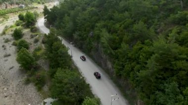 Tepedeki görüntülerde ormanla çevrili yollar boyunca heyecanlı bir cip safarisi görüntüsü var..