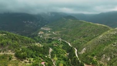 Dağ ormanlarının yoğun yeşilliğine gömülü bir köyün çarpıcı hava manzarası..