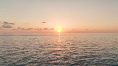 Canlı günbatımı renkleri sakin denizi yansıtır.