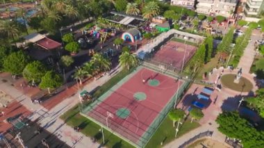 Aerial View: Parlak yaz güneşi altında yoğun bir oyuna katılan oyuncularla dolu canlı bir basketbol sahası.