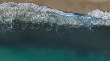 Güneşli bir sahilde eşsiz kum ve dalga desenleri..