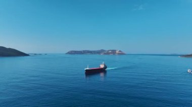 Güneş ufuktan batarken derin mavi denize demir atan etkileyici kargo gemisine bakın..