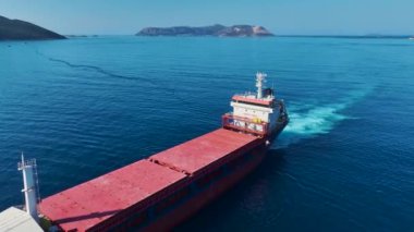 Koyu mavi deniz sularında büyük bir kargo gemisinin demirlediği huzurlu anın tadını çıkarın..