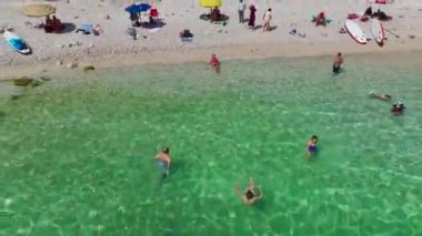 Bikinili bir mankenin berrak, mavi suyu olan sakin bir plajda güneşlenişini izle..