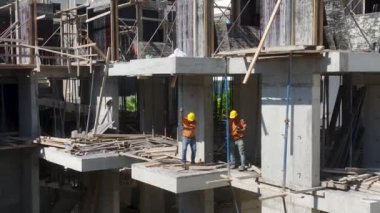 İnşaat işçilerinin yoğun bir inşaat projesine beton dökmek için zemini hazırlamalarına bakın..