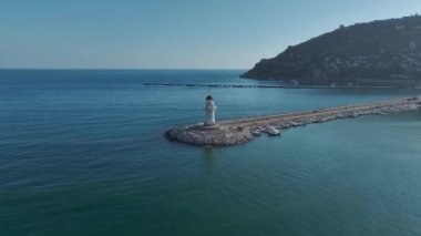 Denizin huzurlu mavi sularına bakan Alanya limanındaki manzaralı deniz fenerine bakın..
