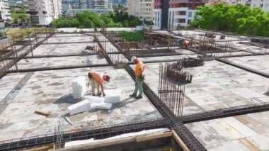 İnşaatçılar inşaat demirini büküyor ve yeni bir inşaat projesi için inşaat alanını hazırlıyorlar..