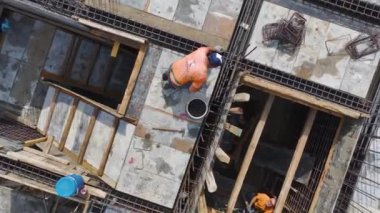 İşçiler demirleri büker ve inşaat projesinin bir sonraki aşaması için zemini hazırlarlar..