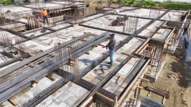 İşçiler demirleri büker ve gelecekte aktif bir inşaat projesi için zemin hazırlarlar.