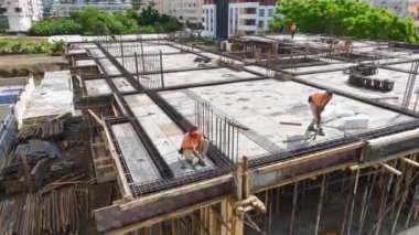 İnşaatçılar inşaat demirini büküyor ve zemini yeni bir inşaat projesinin üzerine beton dökülmesine hazırlıyorlar..