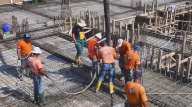 Yeni bir inşaat projesi için inşaat demirini büken ve zemin hazırlayan işçilere bakın..