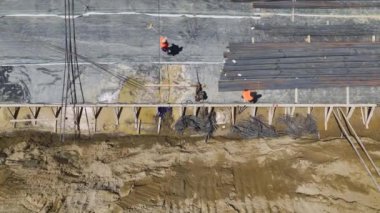 İnşaatçıların inşaat demiri bükmelerini ve inşaat sahasının zeminini hazırlamalarını izleyin..