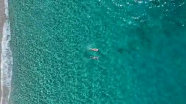 Bir grup, temiz sularla dolu sihirli bir sahilde kürek çekmeyi ve yüzmeyi seviyor..