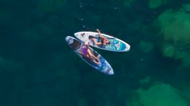 Yüzen, güneşlenen ve kristal berrak suda kürek çeken insanların olduğu çarpıcı bir plaj günü..