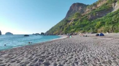 İnsanların kristal berraklığında suyla güzel bir plajda kürek çekişini izleyin..