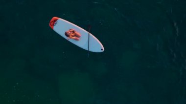 Bir manken, vahşi bir plajda, bikinisiyle poz verirken güneşten zevk alır..