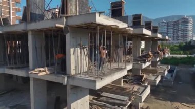 İşçilerin ve makinelerin yüksek binalar inşa ettiği işlek bir inşaat alanı.