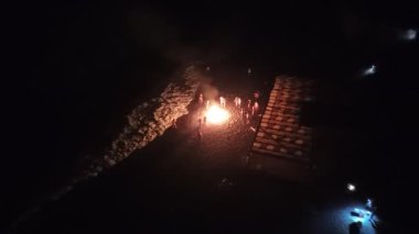 Arkadaşların dans ettiği ve ateşin sıcaklığının tadını çıkardığı canlı bir şenlik ateşi..