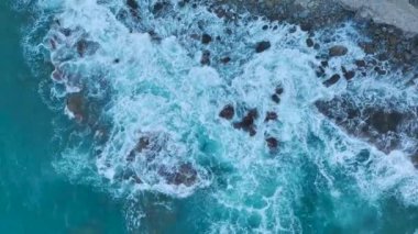 Fırtınalı deniz şafak vakti kayalık kıyıya vurur ve okyanusun güzel dokusunu gösterir..