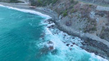 Fırtınalı deniz şafak vakti kayalık kayalıklara çarpar ve okyanus yüzeyinde dramatik dokular yaratır..
