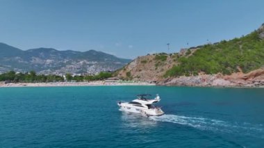 Akdeniz kıyısındaki su aktiviteleri ve plaj oyunlarından keyif alan insanlarla dolu temiz beyaz bir plaj..